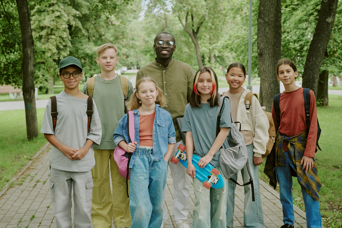 En gruppe af glade børn og unge mennesker i skoven, generation alpha